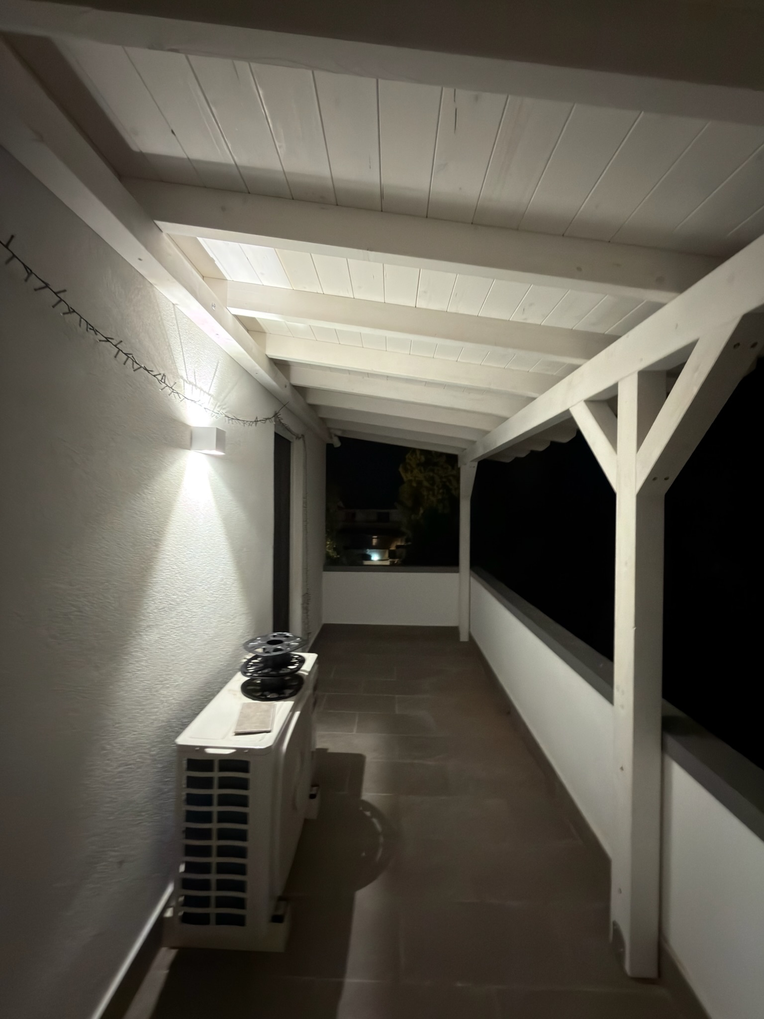Pergolato in legno completato, con copertura, illuminazione e pavimentazione dell’area esterna.