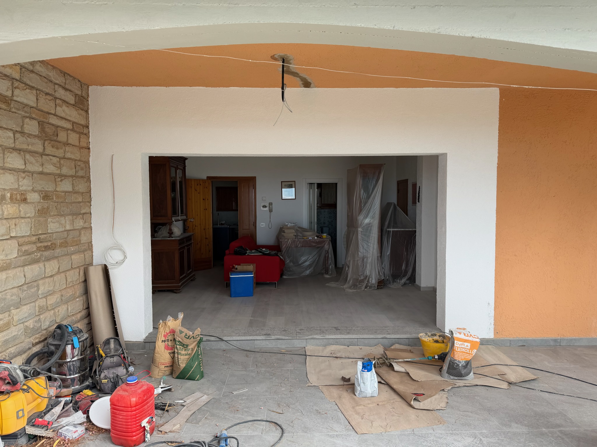 Lavori di ristrutturazione di uno spazio esterno coperto, con nuova pavimentazione e predisposizione degli impianti.